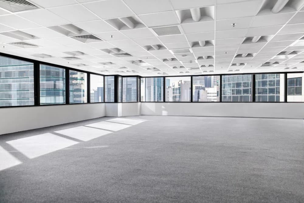 An empty office floor cleared back to bare carpet, ready to hand back