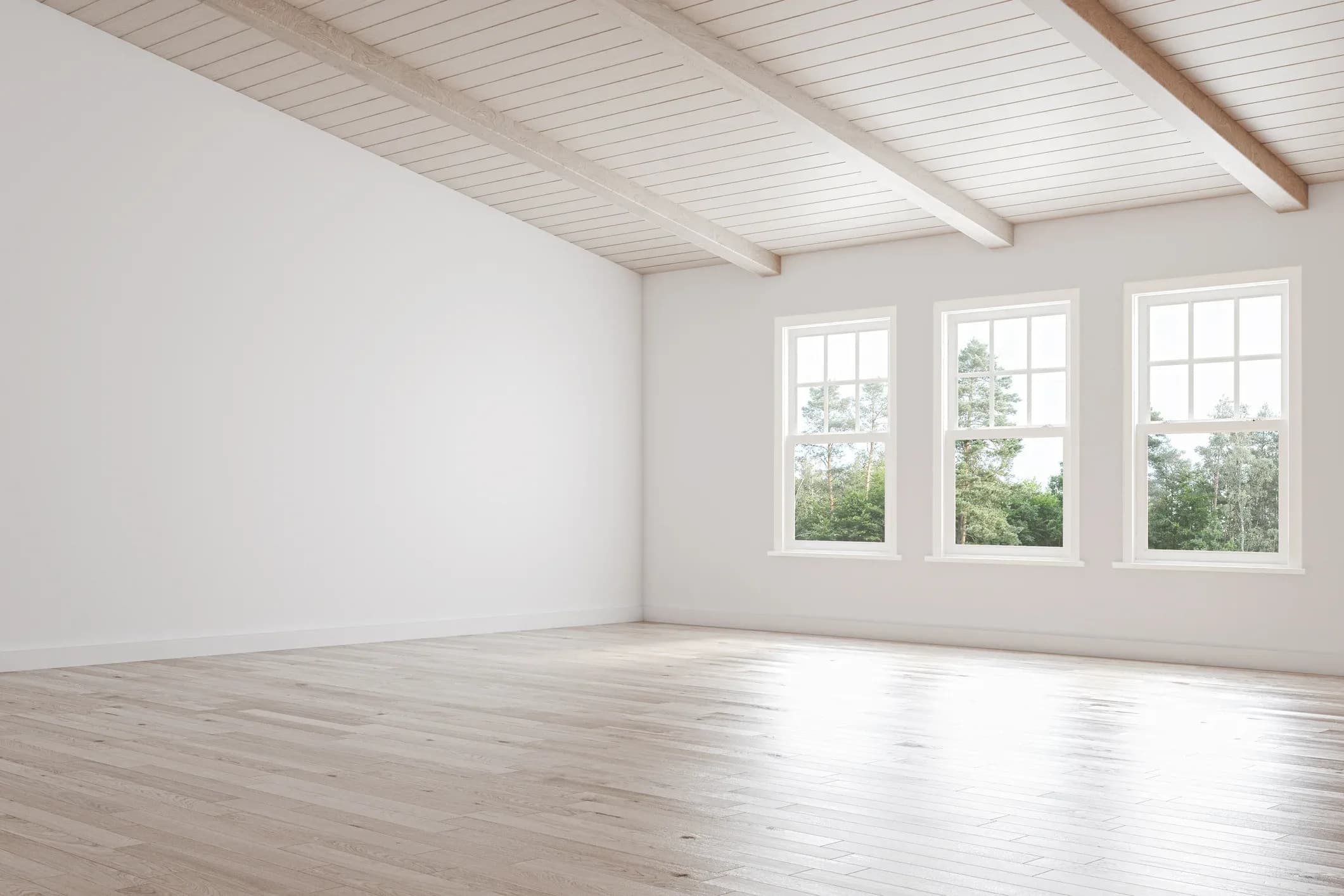 A cleared room with bare wood floors and daylight through three windows