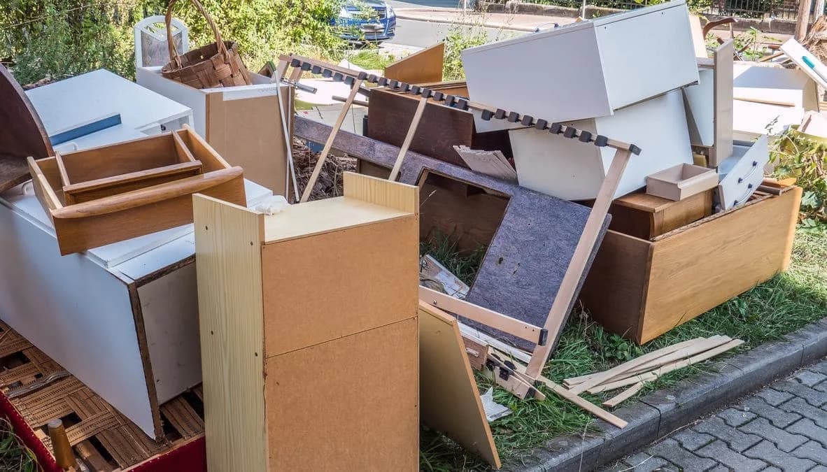 A curbside pile of old dressers, drawers and flat-pack furniture waiting to be hauled